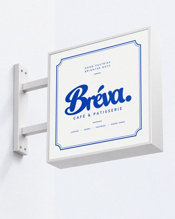 Wall mounted cafe sign mockup featuring a framed white sign with bold blue typography and a decorative border, presented in a clean, minimalist studio setting.