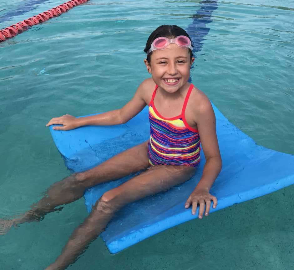 Ella relaxes after some racing and fun during Little Kickers before school, at the Rainbow Beach Aquatic Centre