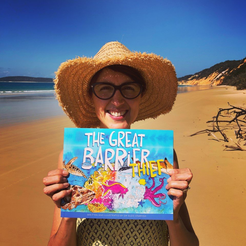 Dr Suzie with her first picture book at Rainbow Beach