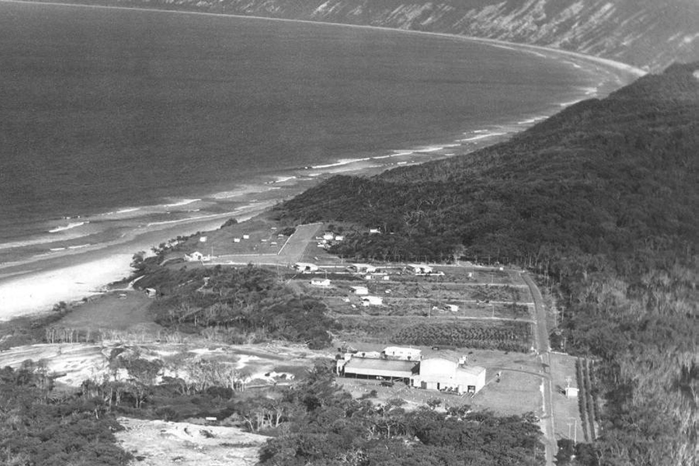 An aerial photo of Rainbow Beach from 1965 showing the Mineral Sands Building, the three mining houses, the Surf Club, Phil Rogers’ shop and a few caravans (supplied Garry Hewitt)