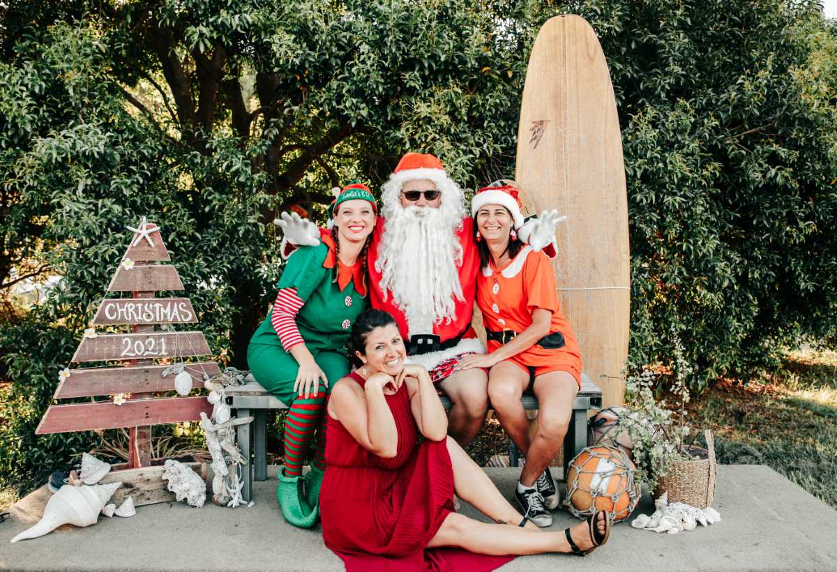 Santa and his elf last year with event organiser Elisa Seul and sleigh co-pilot Di from Rainbow Beach Helicopters. Get yourse