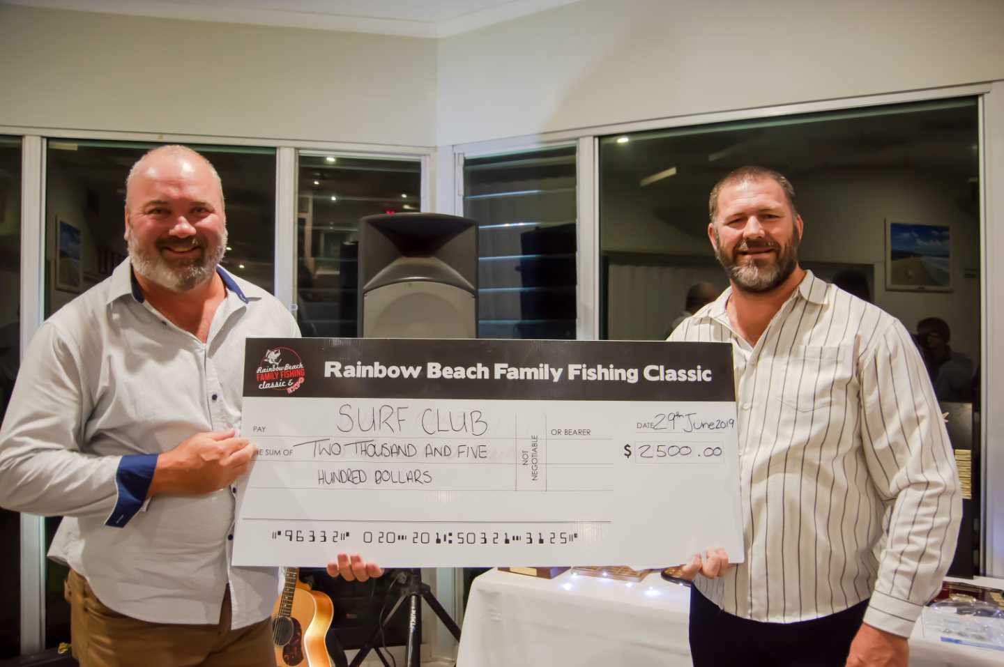 Kroppy handing Shane Handy a cheque for the surf club from the proceeds of the Bull ‘n’ Bronc  