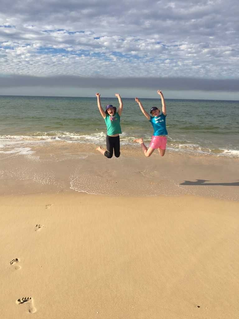 12-year-old twins, Olivia (left) and Jacinta Sullivan are jumping for joy to be at the best winter beach away from cold Toowo