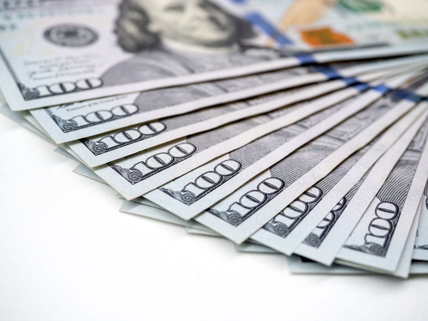 Hundred-dollar bills fanned out on a white surface