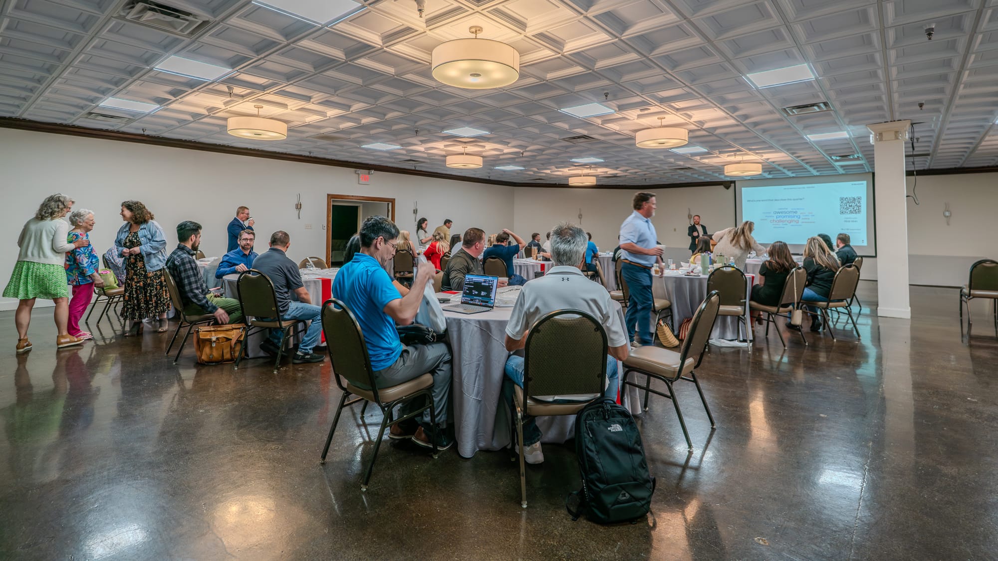 Wide view of the Kings of Real Estate Town Hall meeting with team members seated at round tables