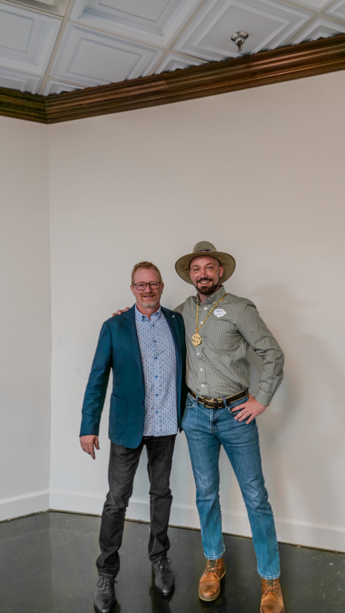 Team member posing with Tracy King wearing the gold chain award at Kings of Real Estate