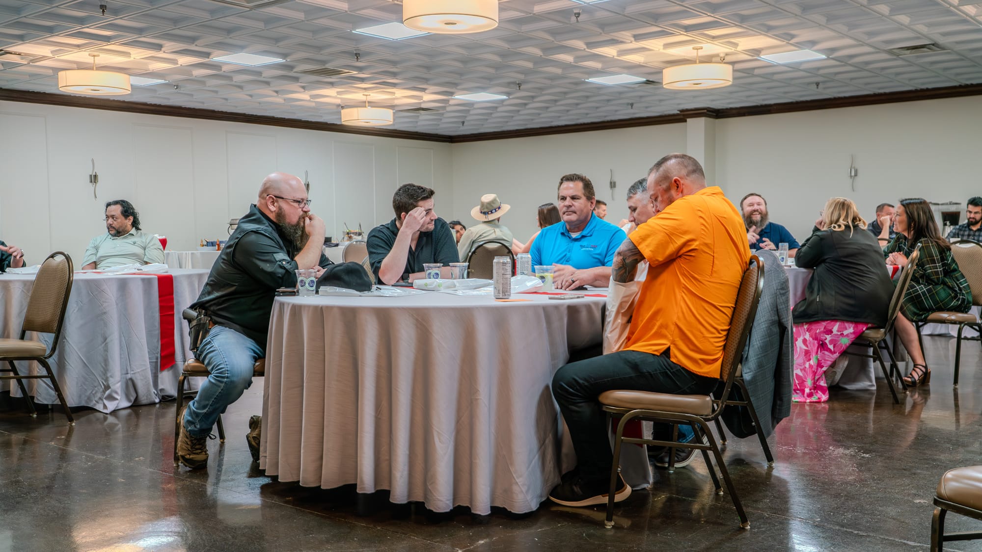 Team members in deep conversation at round tables during Kings of Real Estate Town Hall