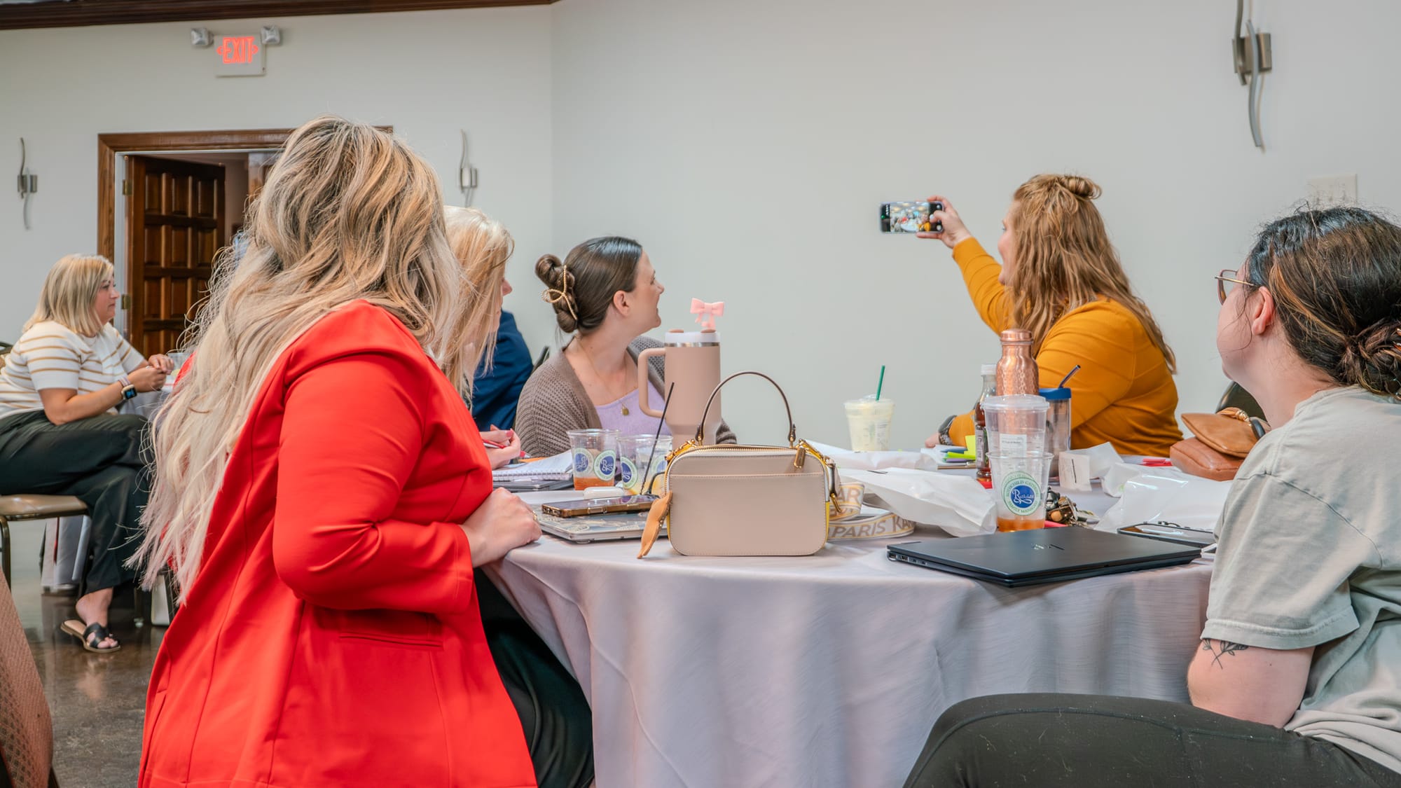 Team members at a table taking notes and photos during the Kings of Real Estate Town Hall