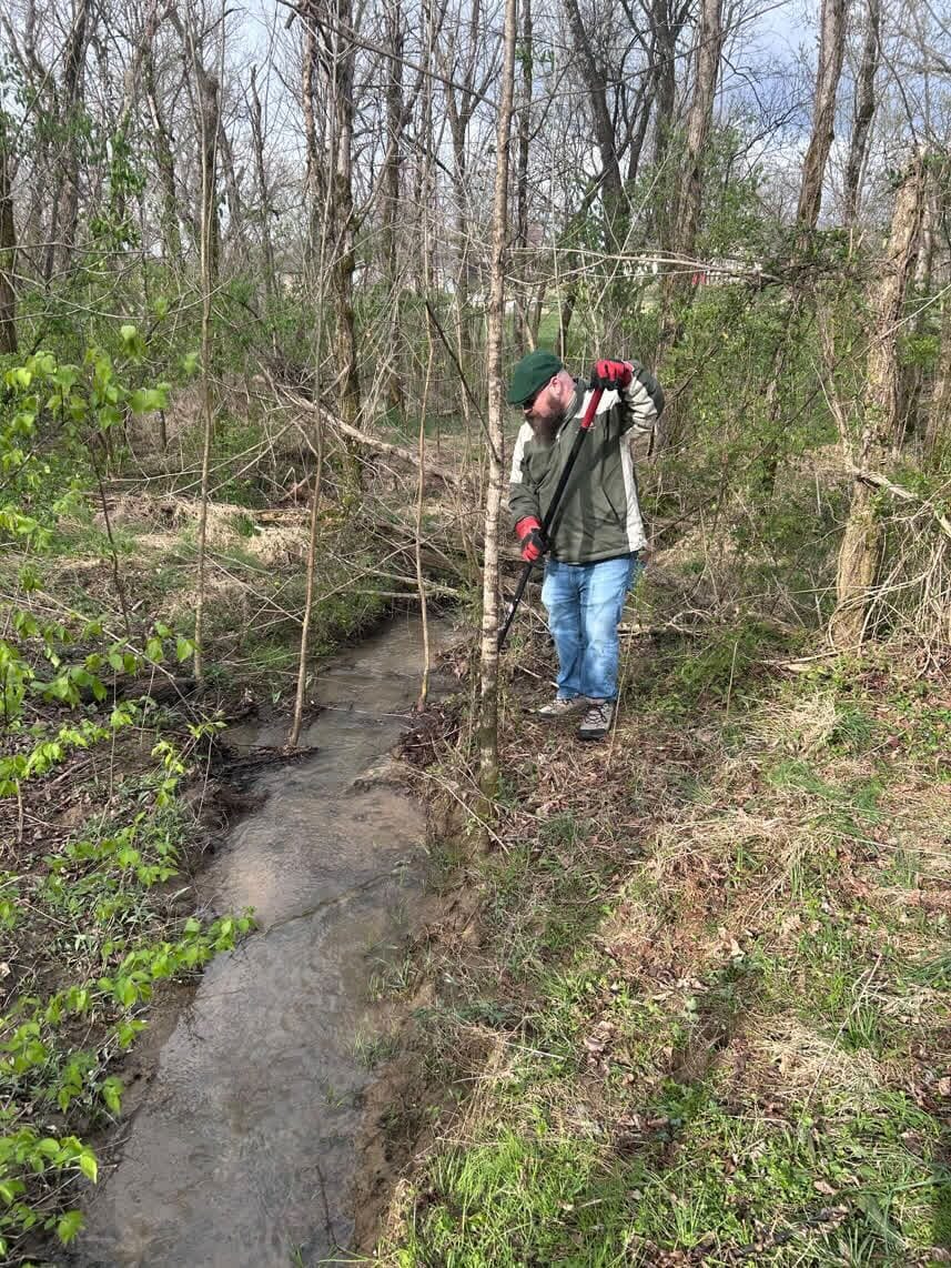 A volunteer clearing brush along a creek bed