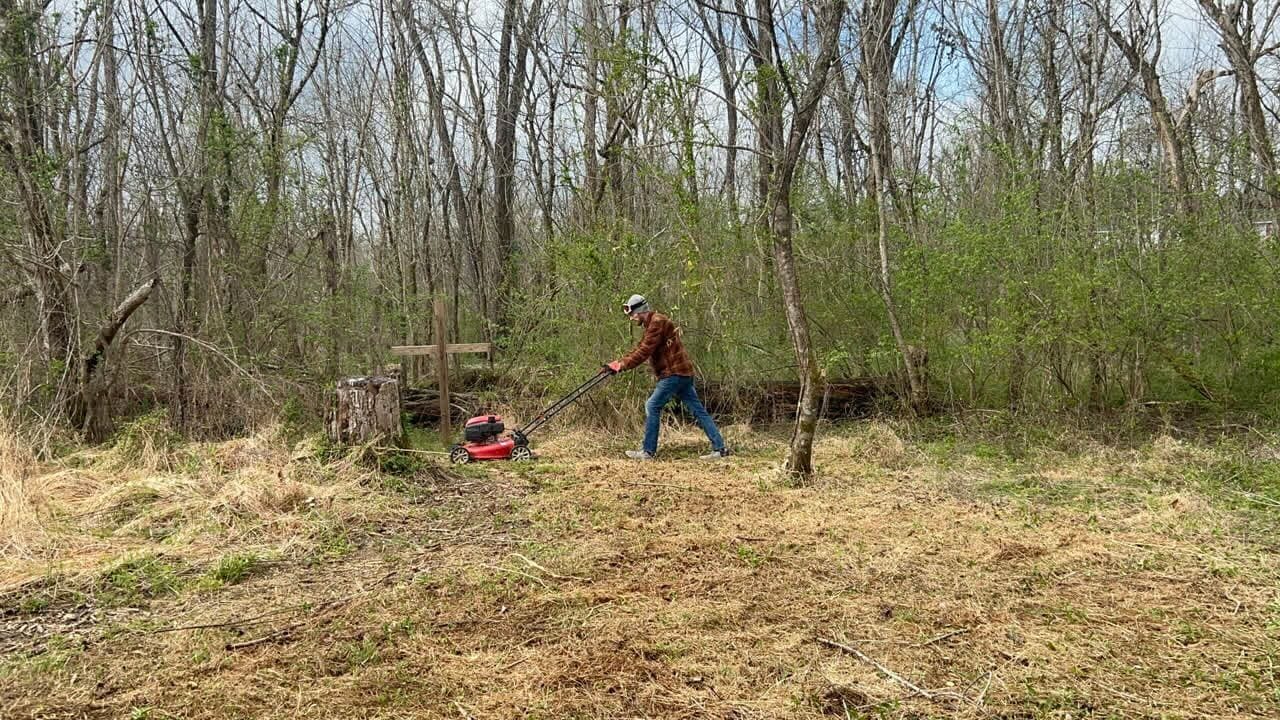 A volunteer mowing overgrown grass at LIVE-IT Ministries