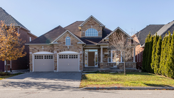 Stone and brick two-story home with a two-car garage and an autumn tree in the front yard