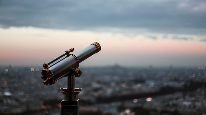 Telescope pointed at the sky over a city at dusk