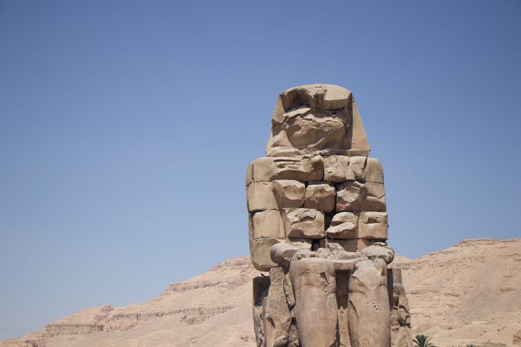A crumbling Egyptian statue in the desert.