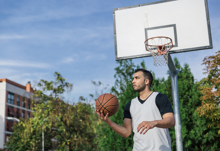 A man shooting a basketball during daytime, representing the common fantasy of effortless living contrasted with the hidden structures of modern employment.