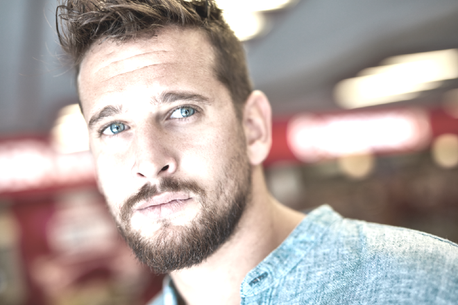 Young man with a slight beard, gazing beyond the camera.