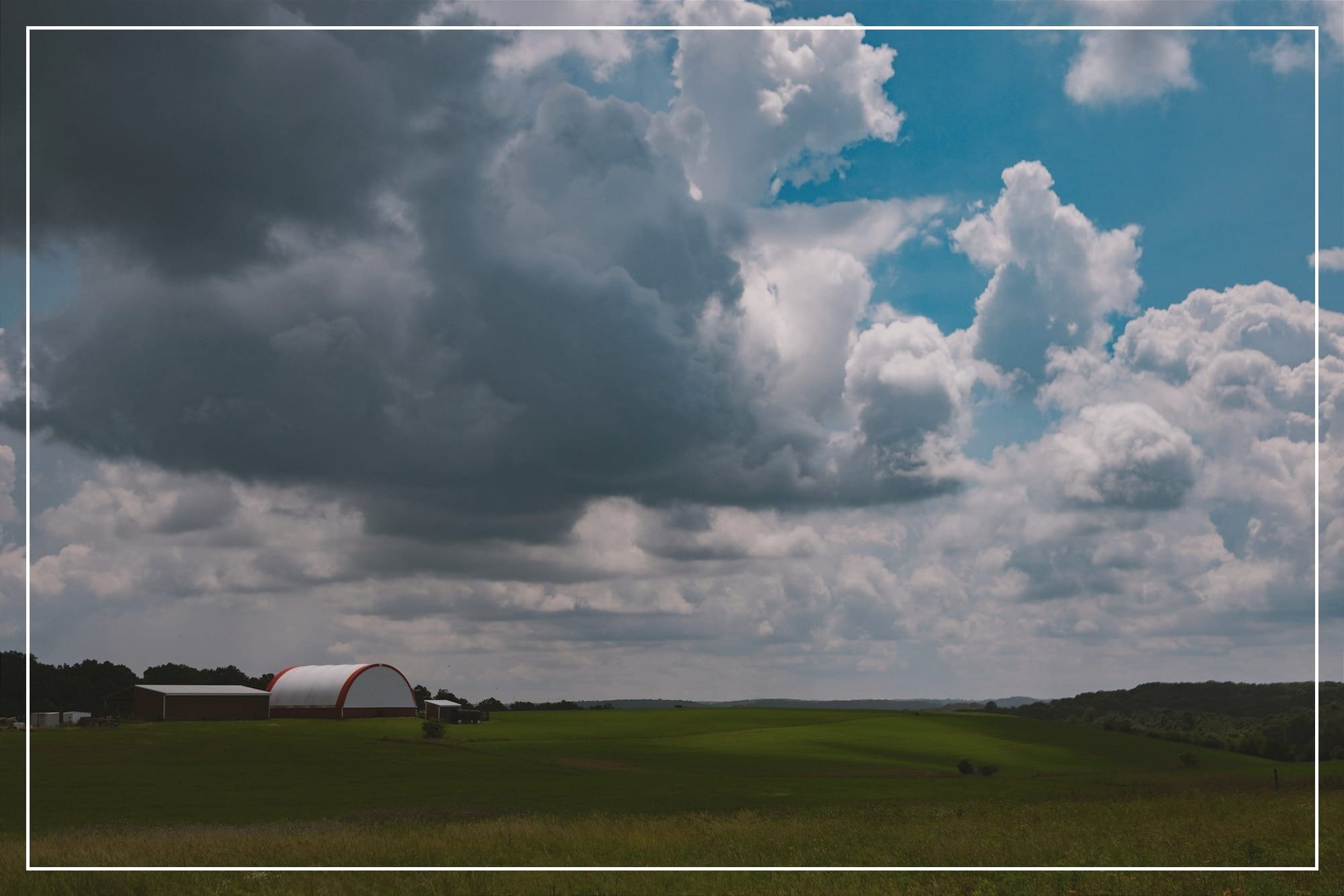 Green fields, fluffy clouds, and a distant farm.