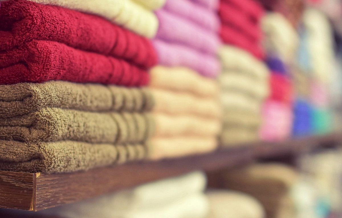 Close-up of neatly stacked towels in multiple colors on a store shelf, arranged to look full and orderly.