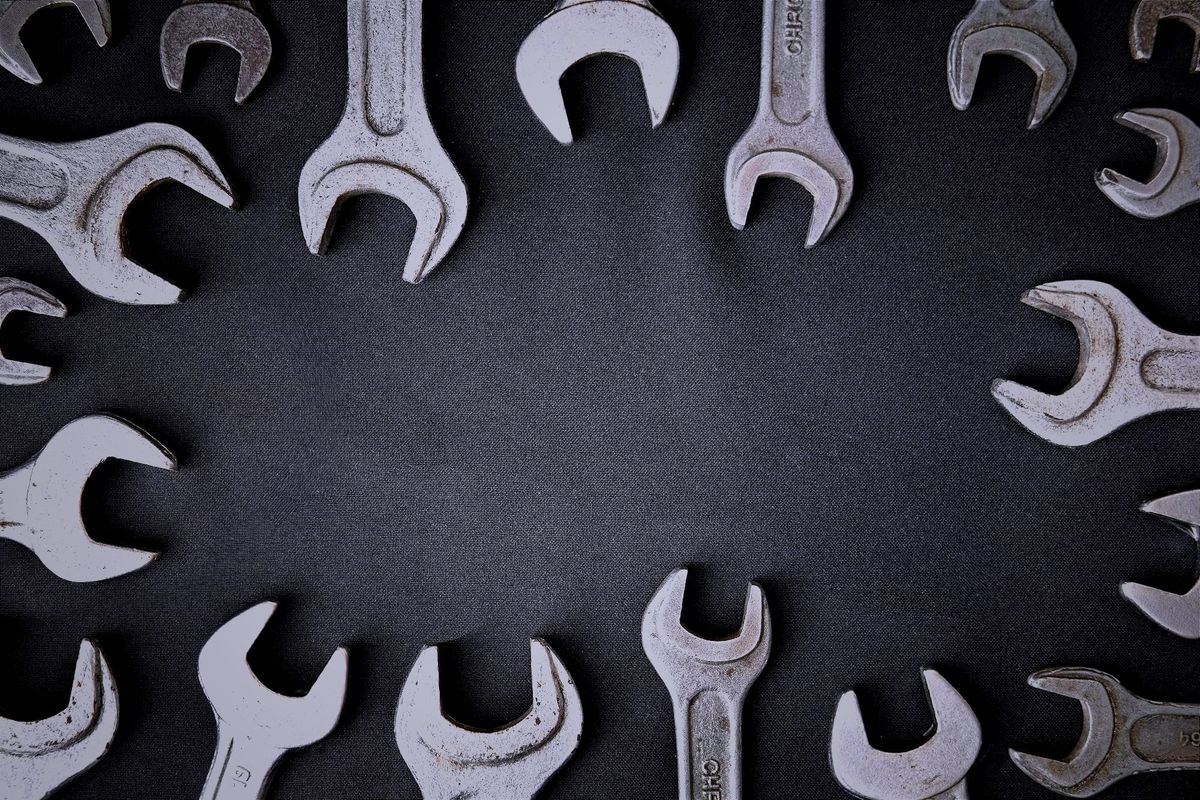 A ring of metal wrenches arranged around the edges of a dark textured surface, leaving an empty space in the center.