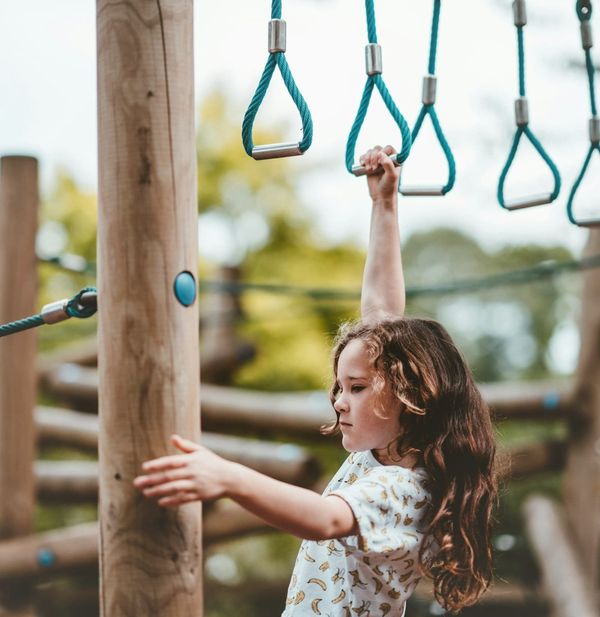 A girl swinging on monkey bars.