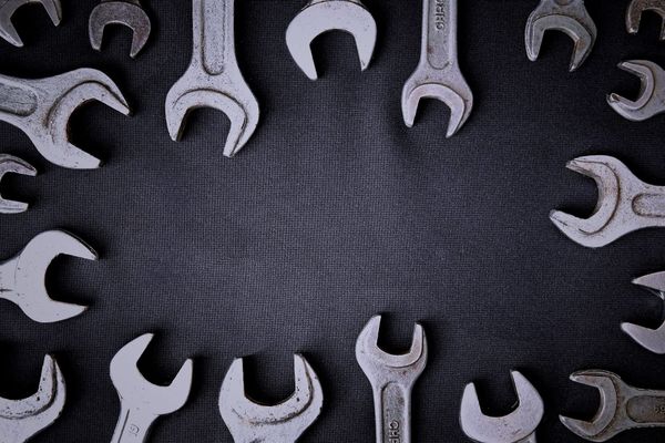 A ring of metal wrenches arranged around the edges of a dark textured surface, leaving an empty space in the center.