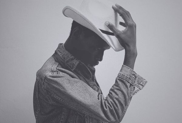 Black-and-white photo of a Black man in a denim shirt tipping a white cowboy hat, used as a metaphor for hero identity and visible rescue.