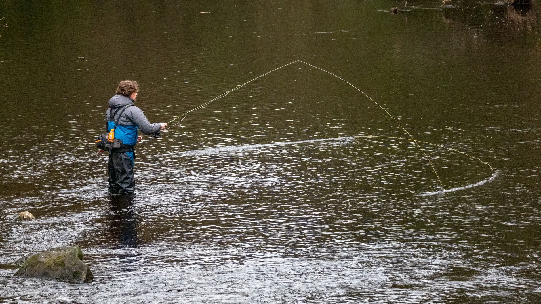 Man fly fishing in River Nidd, Knaresborough, UK, showcasing angling skills.