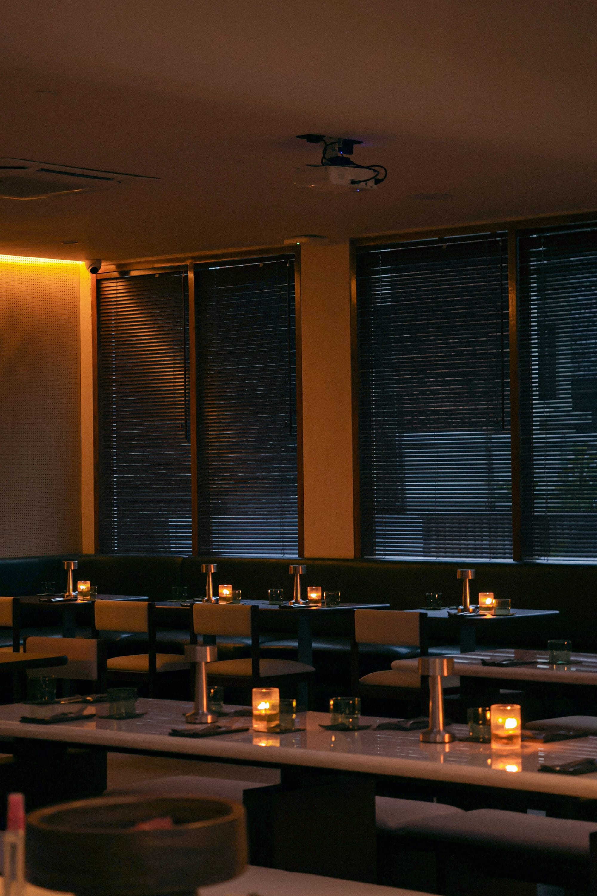 Green velvet banquette seating and dark wood tables inside nüde Berawa, the new evening restaurant on Jl. Pantai Berawa.