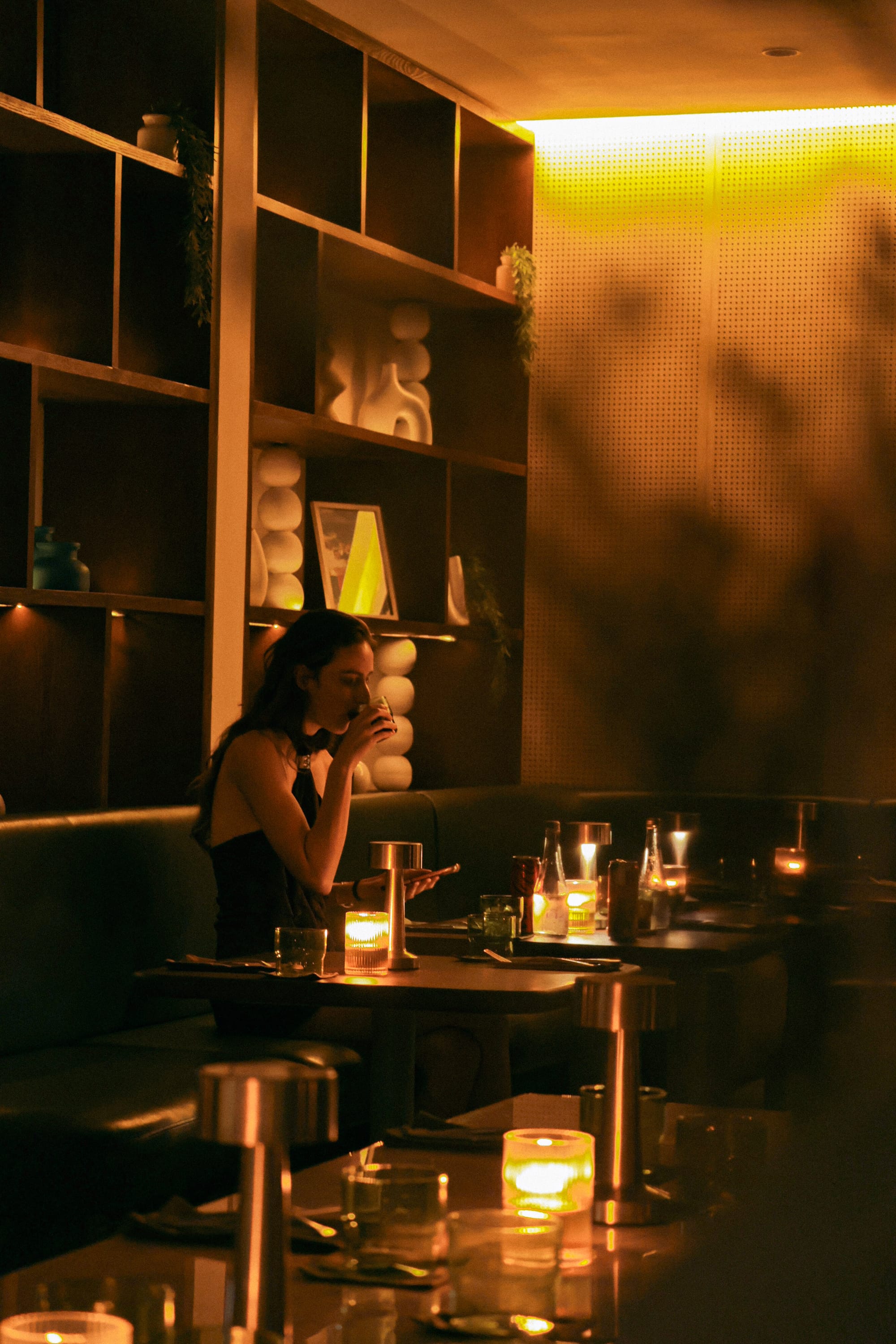 Dimly lit dining room at nüde Berawa's new Canggu dinner service, with candlelit tables and projector visuals on the wall.