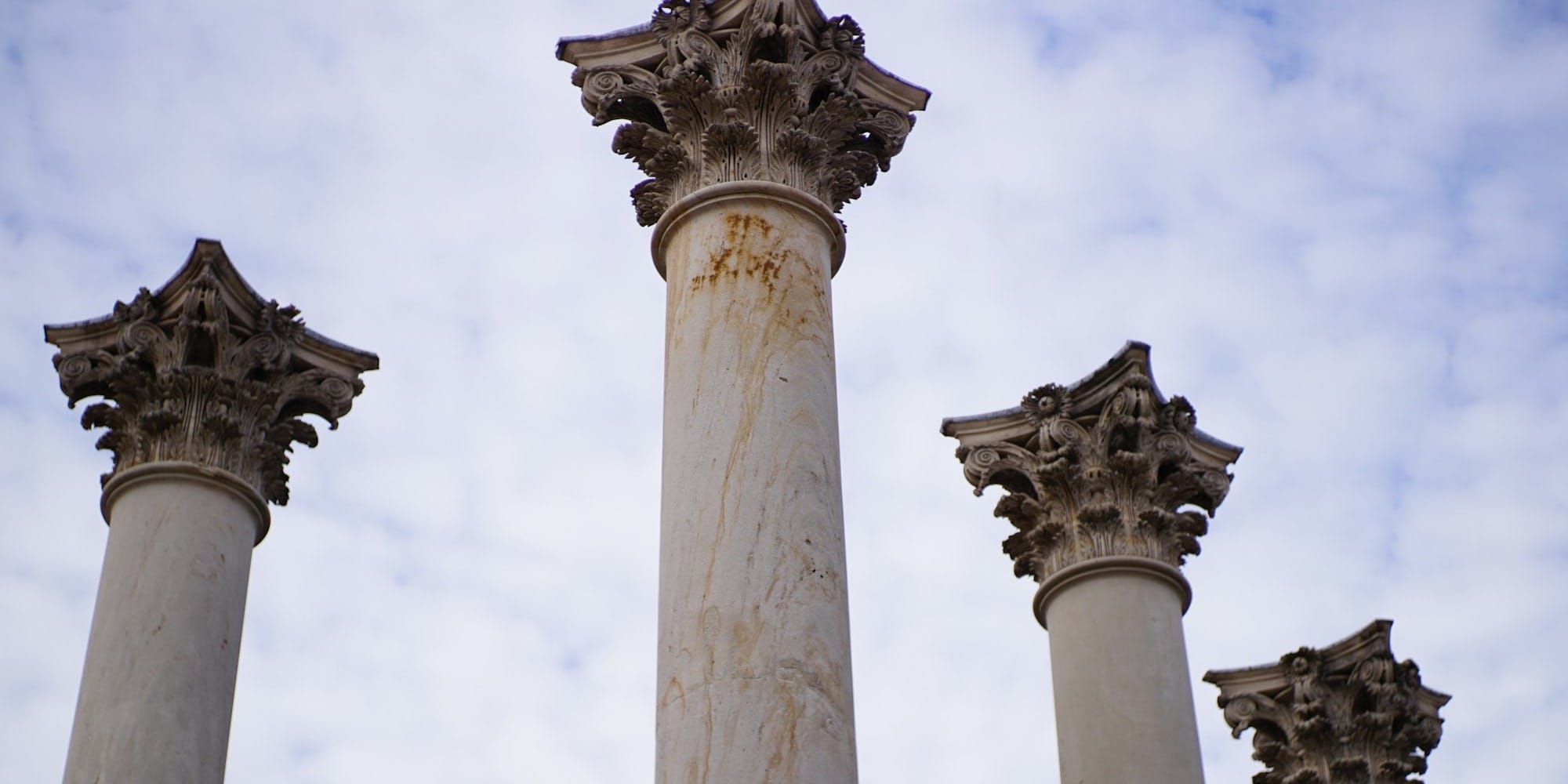 white concrete pillar under white clouds during daytime
