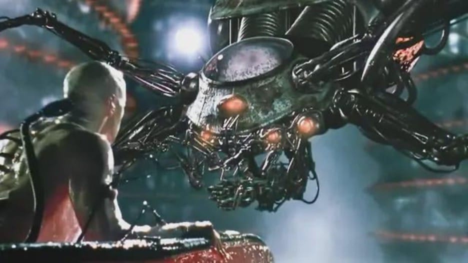 A spider-like machine confronts Neo as he emerges from a womb-like pod in the movie The Matrix.