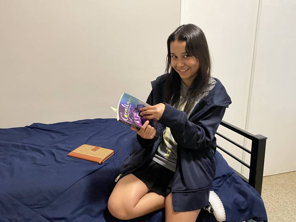 Zhayreth Torres les muestra a los reporteros de GBH su habitación y un libro que está leyendo para inglés de octavo grado.
Foto de Sarah Betancourt, GBH Noticias
