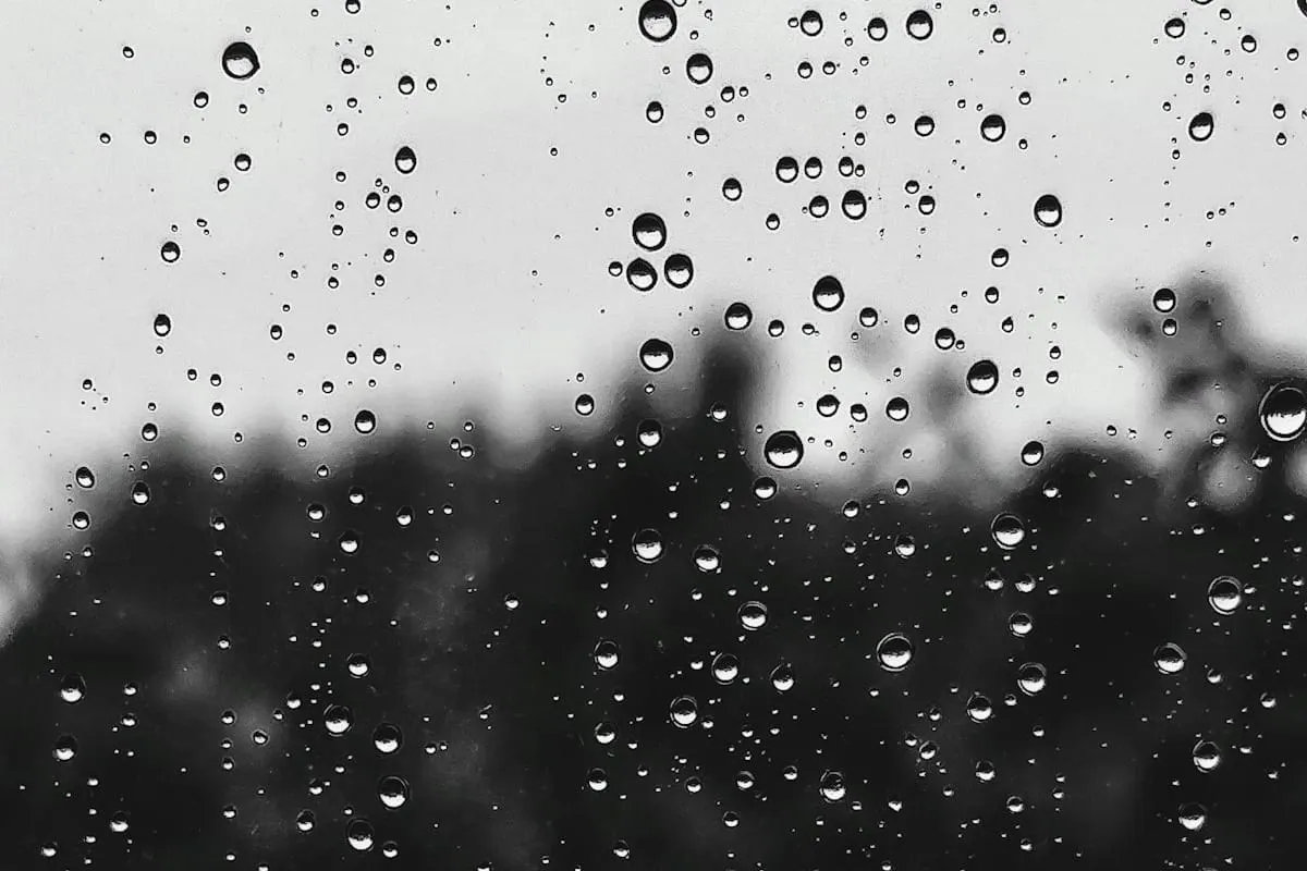 Lluvia intensa sobre una calle urbana con charcos reflejando las luces de la ciudad