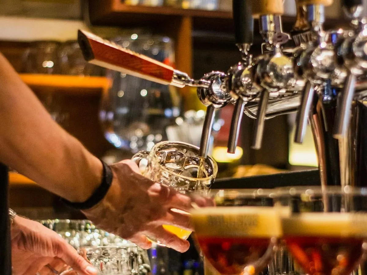 Un bartender sirve una cerveza en la barra de un bar