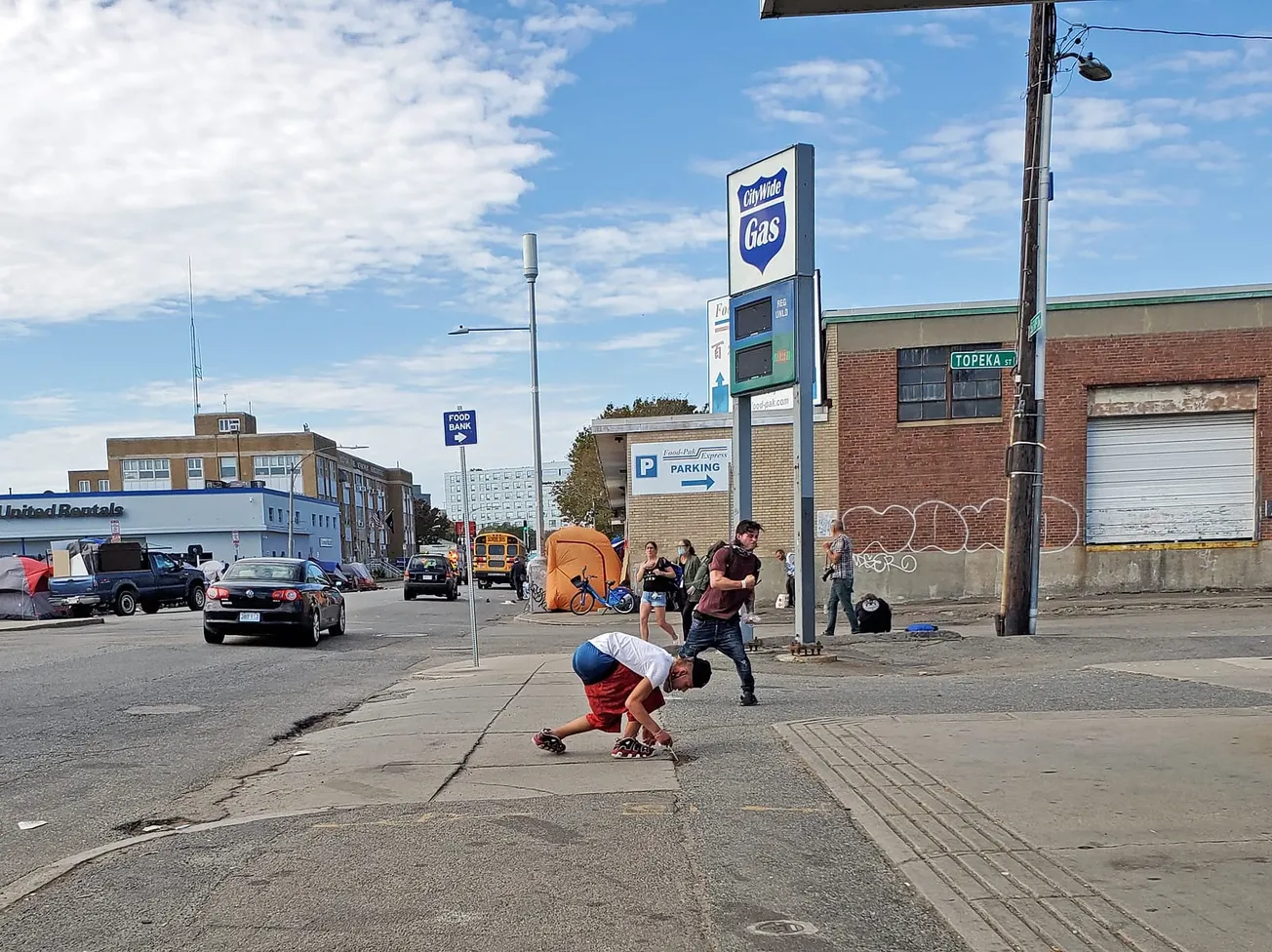 A lo lejos, las carpas que antes se encontraban en Mass & Cass. Más cerca, algunos jóvenes, en ellos, uno buscando desperdici