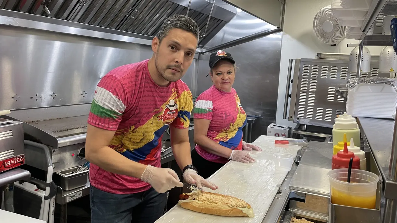 Andrés Jaramillo es el dueño de “Perros Paisas” junto a Carmen Isabel Giraldo preparando, en la cocina del restaurant, uno de