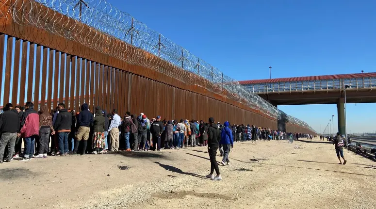 Migrantes mientras hacen fila para entregarse a la Patrulla Fronteriza estadounidense el 21 de diciembre, en la valla fronter
