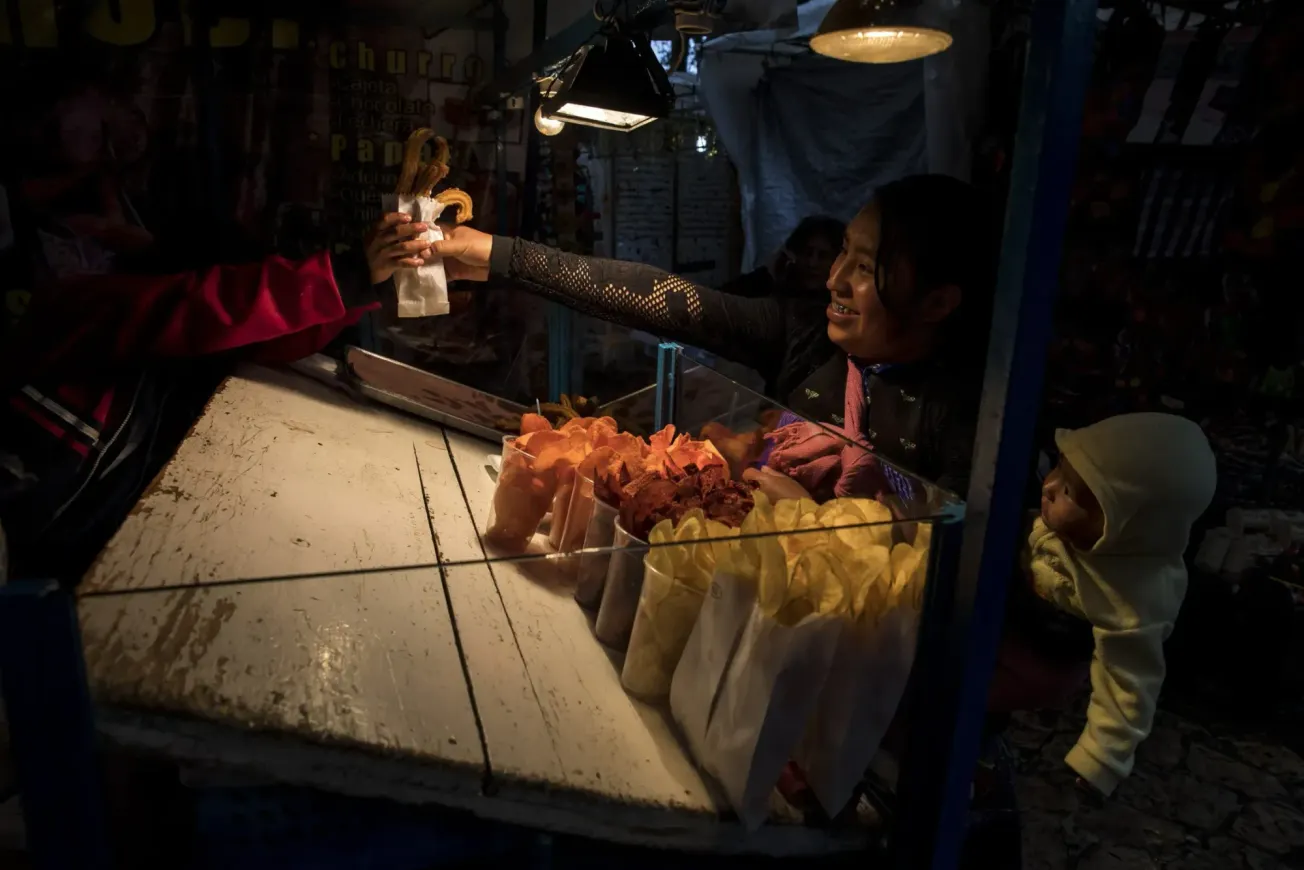 Una mujer compra churros para sus hijos en un mercado callejero en San Cristóbal de las Casas, México. | Foto de archivo de J