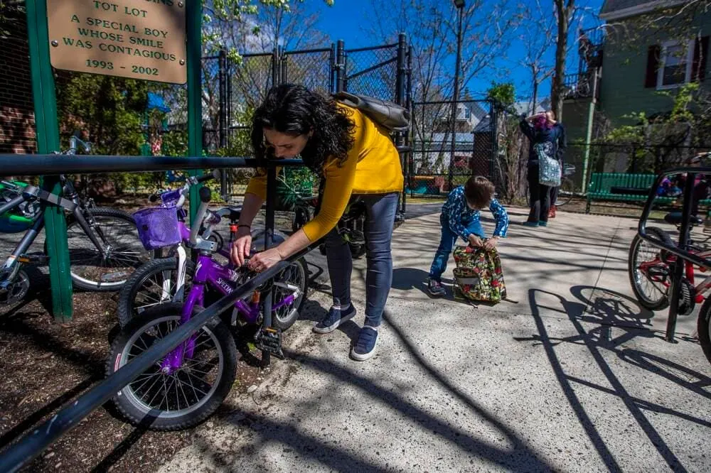 Una madre abre la bicicleta de su hijo antes de regresar a casa. (Jesse Costa/WBUR)