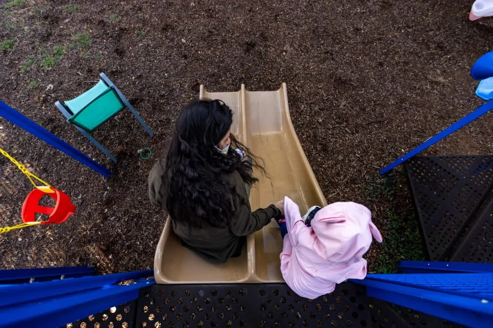 Una madre y su hija de dos años en el patio de juegos del refugio donde se hospedan. (Jesse Costa/WBUR)
