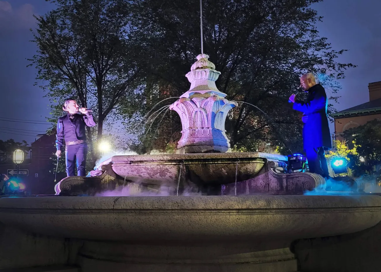 Armando Rivera como Hamlet y Paul Benford-Bruce como el fantasma de su padre, se encuentran en la fuente de la Plaza Chelsea