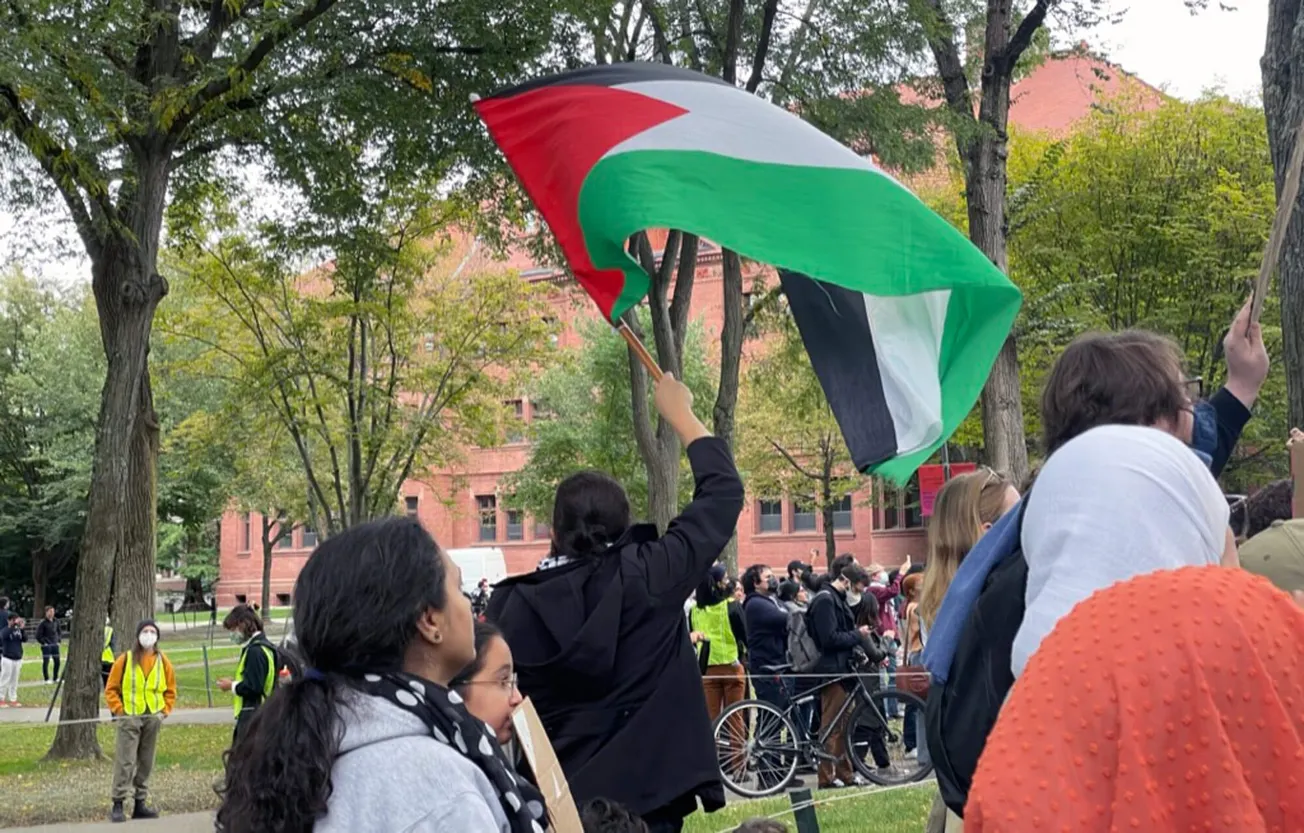 Un manifestante ondea una bandera palestina en una manifestación el 14 de octubre en Harvard Yard. (Max Larkin/WBUR)
