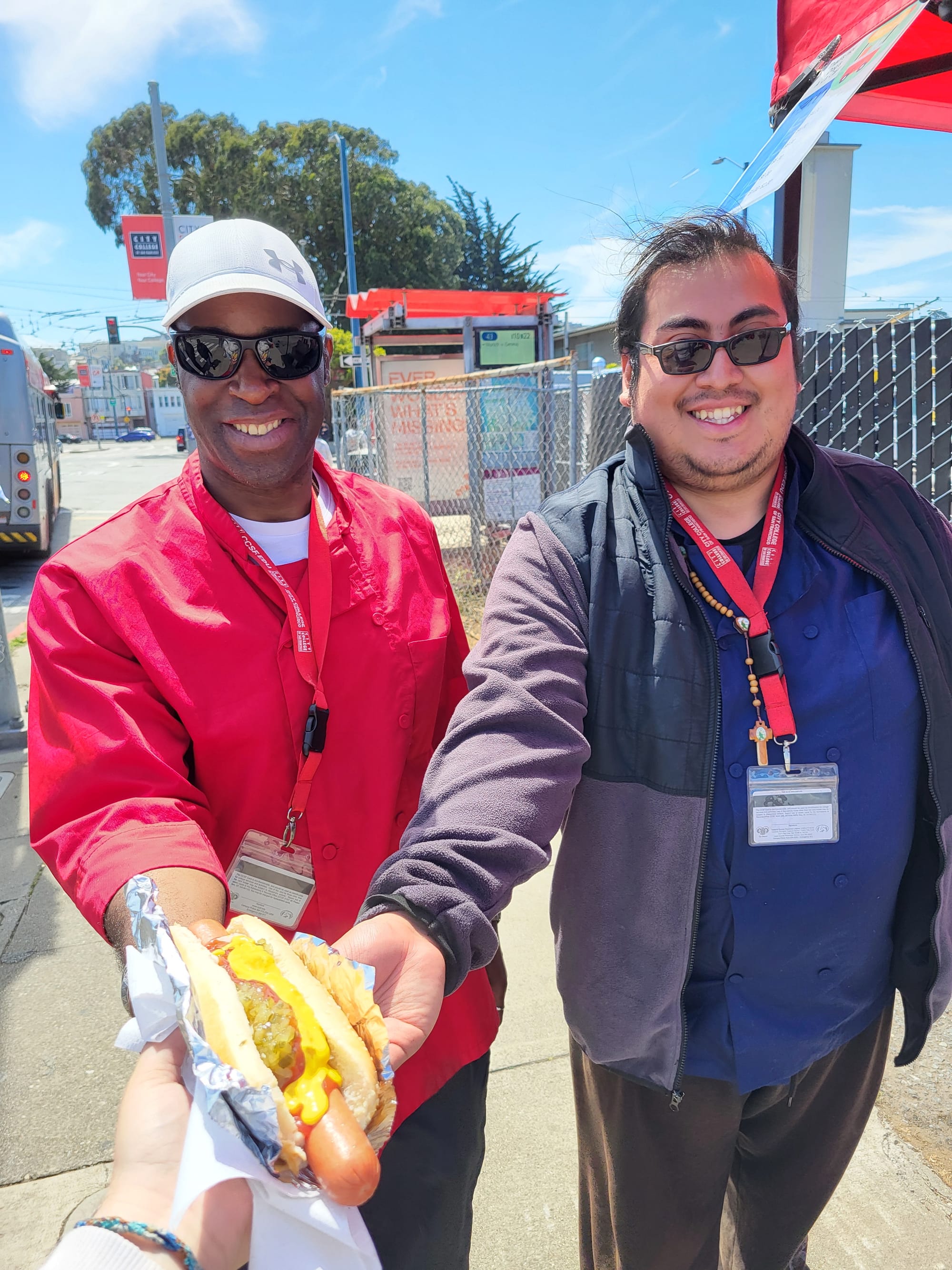Men handing a hot dog.