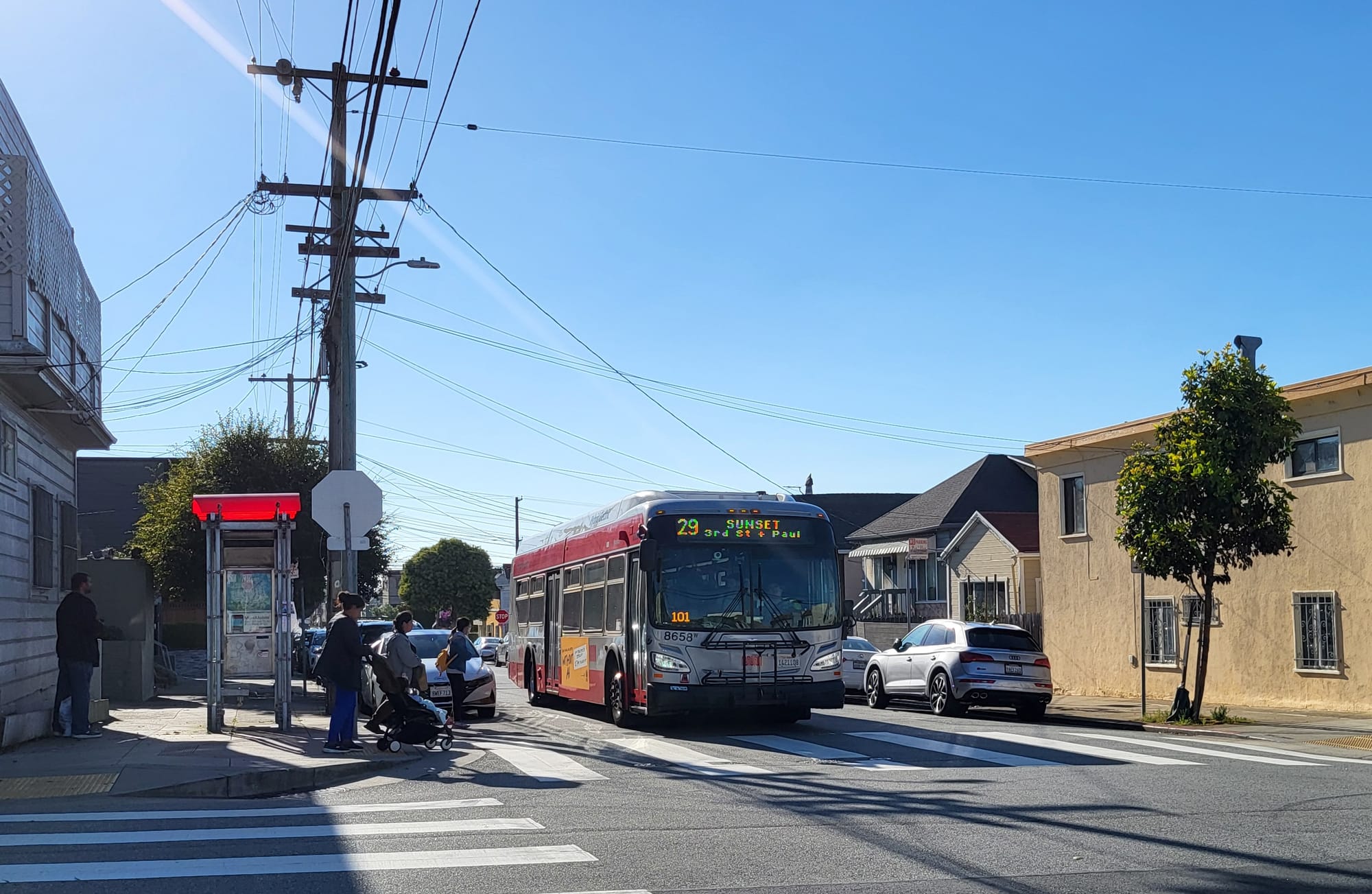 Bus at stop with riders waiting to board.