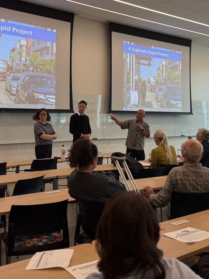 Three people stand in front of an audience.