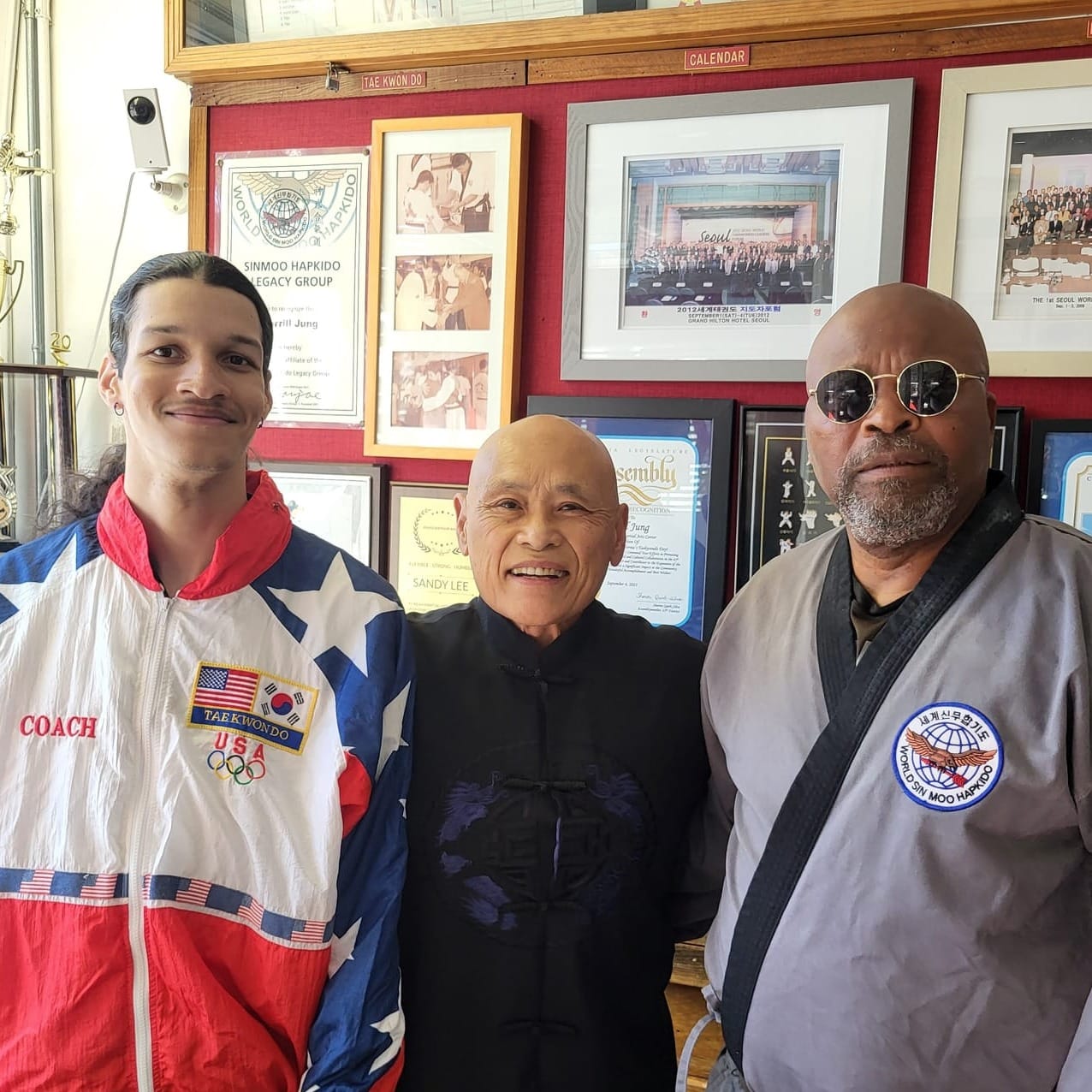 Three men in martial arts attire pose for a photo.