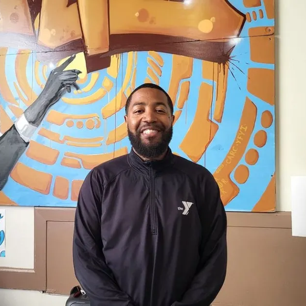 Man with YMCA jacket posing for photo.