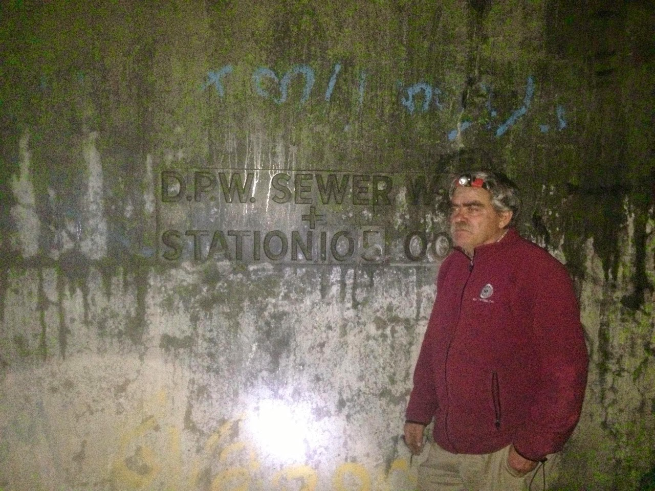 Man in front of a sewer wall.
