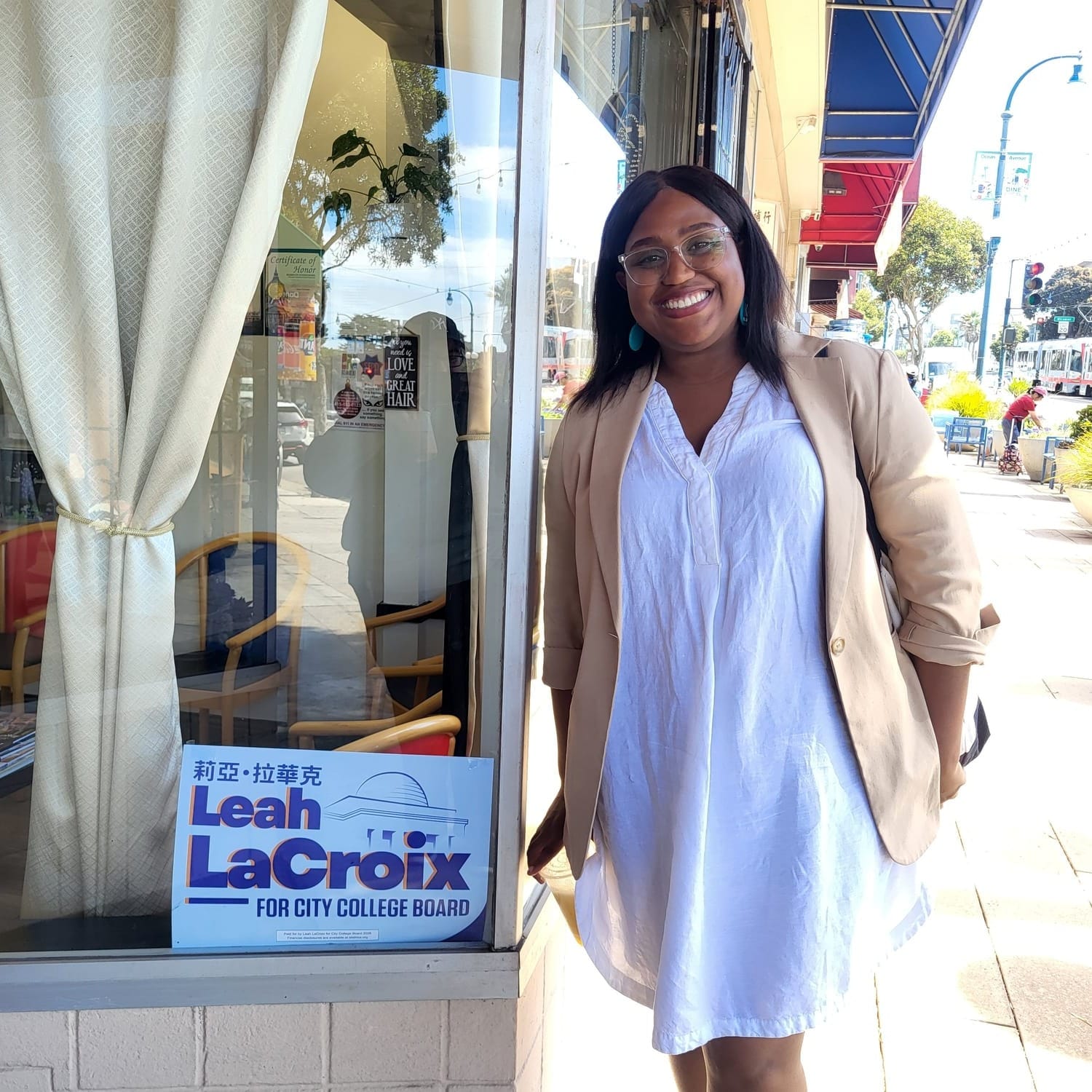 A woman poses beside a campaign sign.