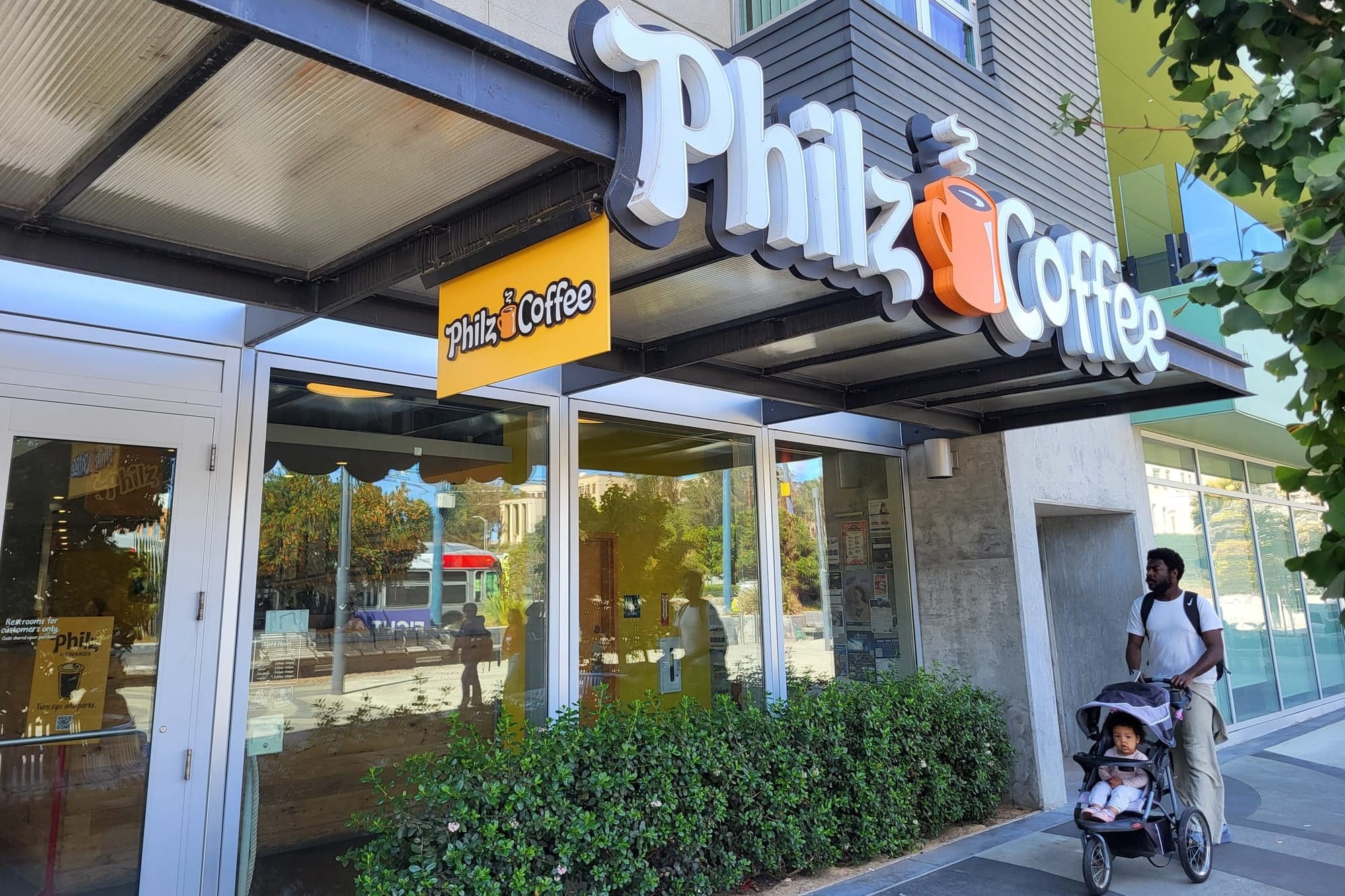 A man with child go past a cafe.
