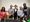 Five people stand behind a table with microphones.